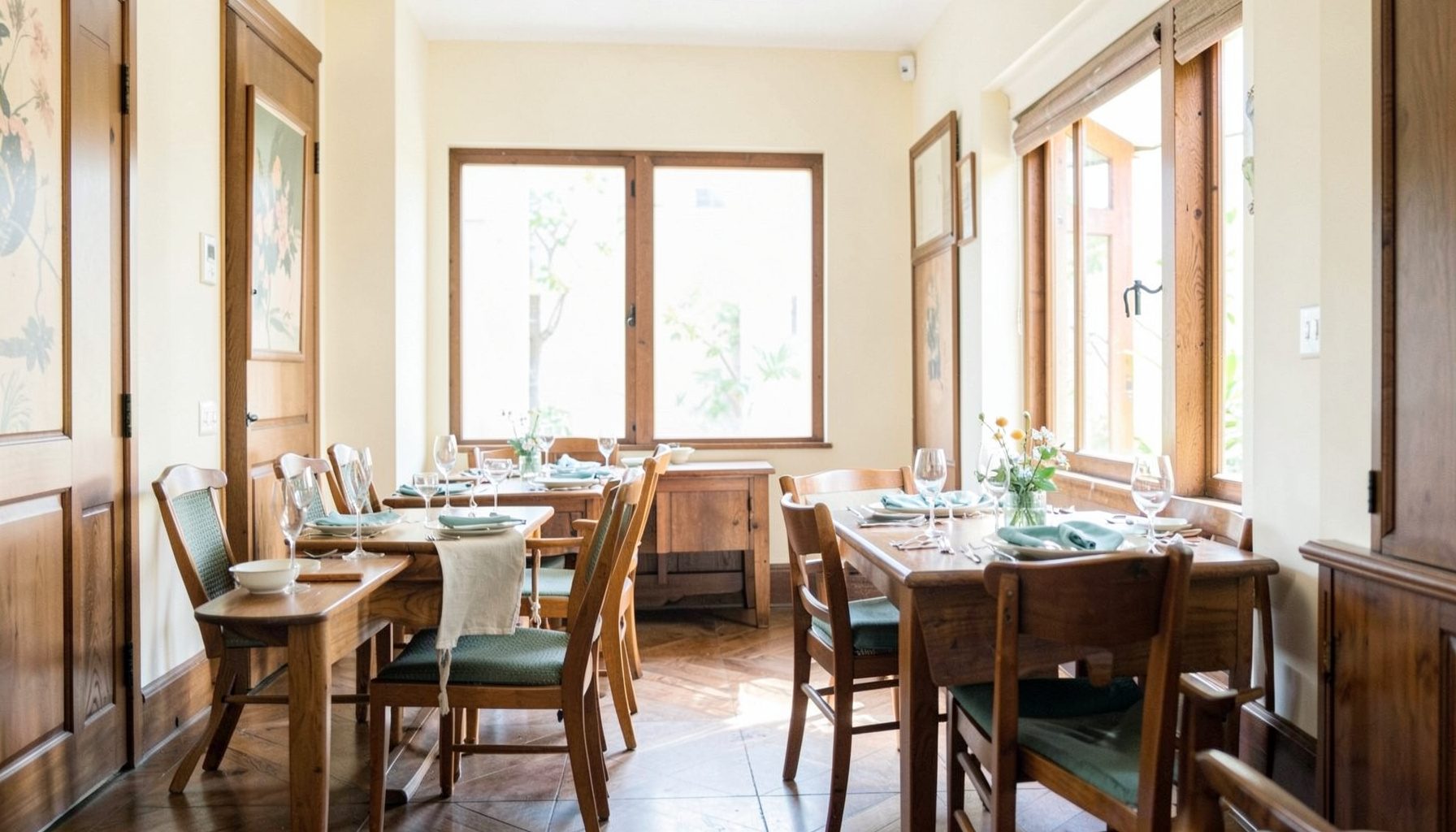 Sunlit heritage shophouse interior with warm wood tones, soft cream walls, and elegant table settings
